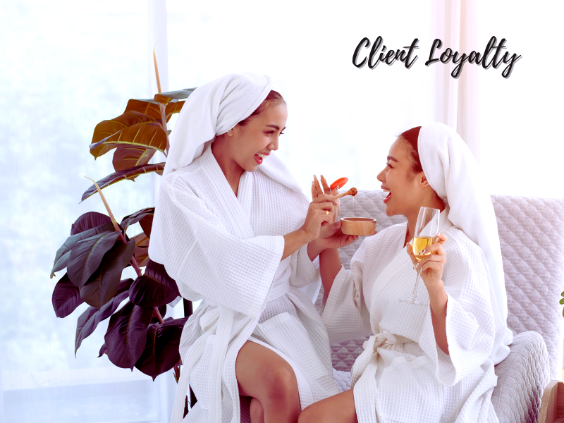 Two women in spa robes sharing a joyful moment, embodying client loyalty and the benefits of advanced skincare solutions.