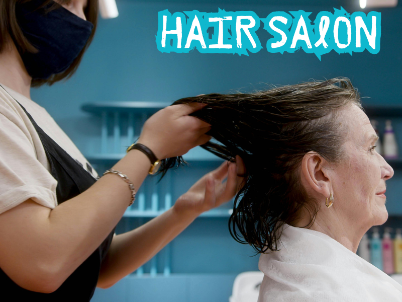 Hairdresser washing older woman's hair in a salon, showcasing gentle scalp and hair care.