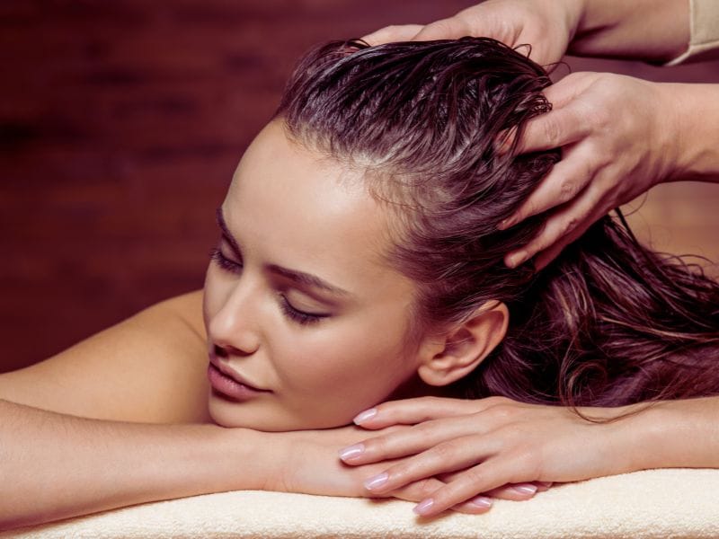 Relaxing salon hair oiling treatment – a client enjoying a luxurious scalp massage with nourishing oil for deep hydration and hair health.
