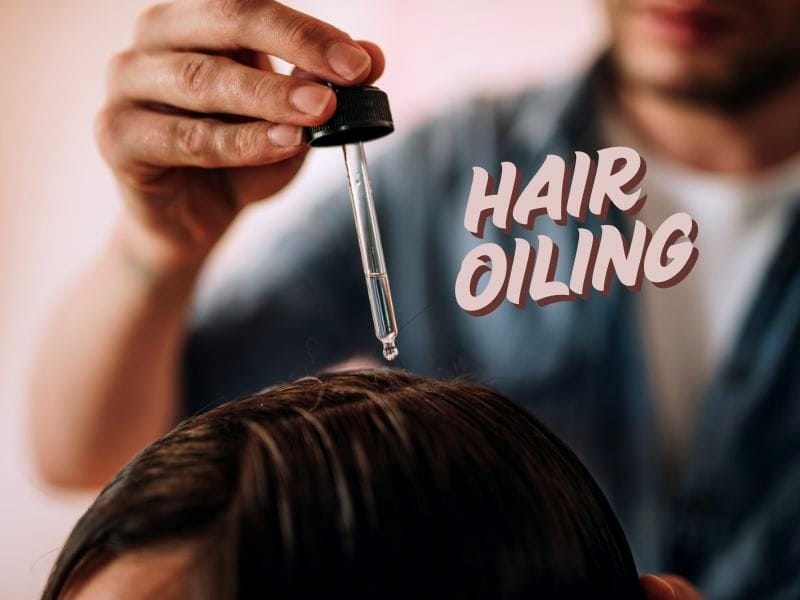 Professional hair oiling treatment in a salon – a stylist applying nourishing oil to a client's scalp using a dropper.