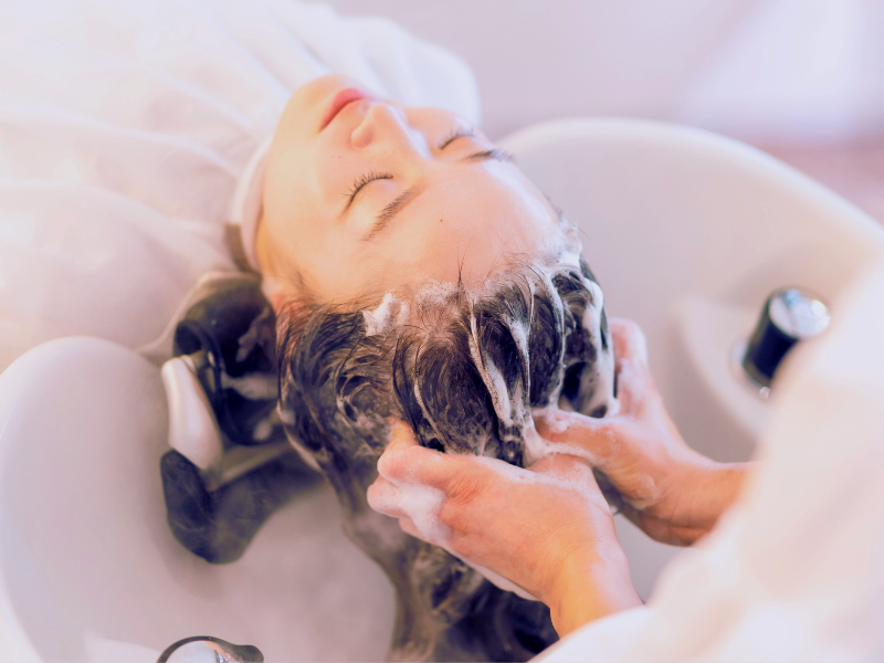 Client receiving a calming scalp massage with European-approved, FDA-compliant vegan shampoo during a salon hair ritual for sensitive scalps.