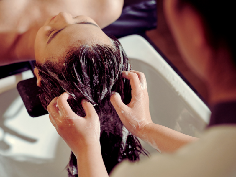 Salon professional giving a relaxing deep conditioning scalp treatment with foamy vegan haircare.