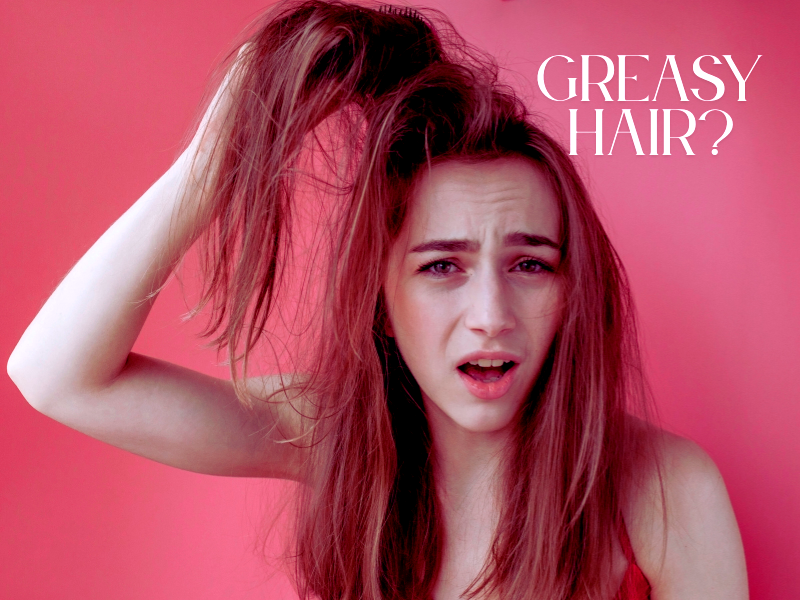 Frustrated woman lifting oily hair, showing concern—highlighting the need for real greasy hair fixes.