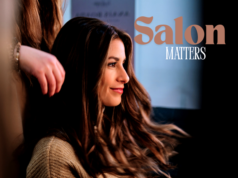 Smiling woman in salon chair with styled hair—showcasing the power of expert salon care that matters.