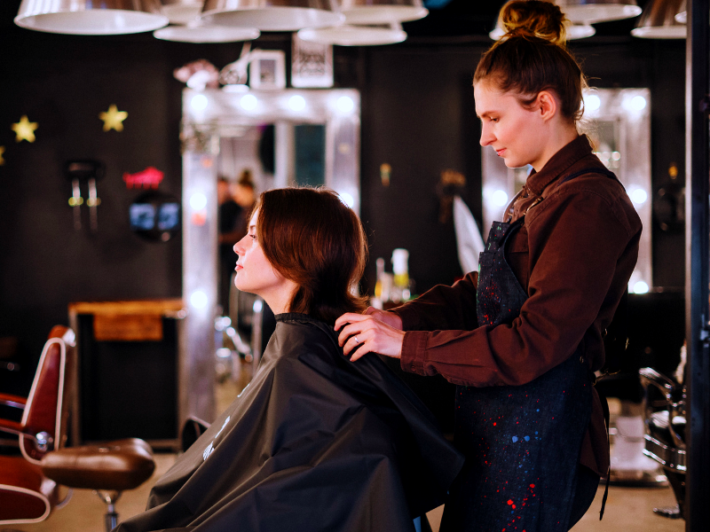 Hair stylist consulting with a client in a salon, preparing for a scalp-focused clean beauty treatment.