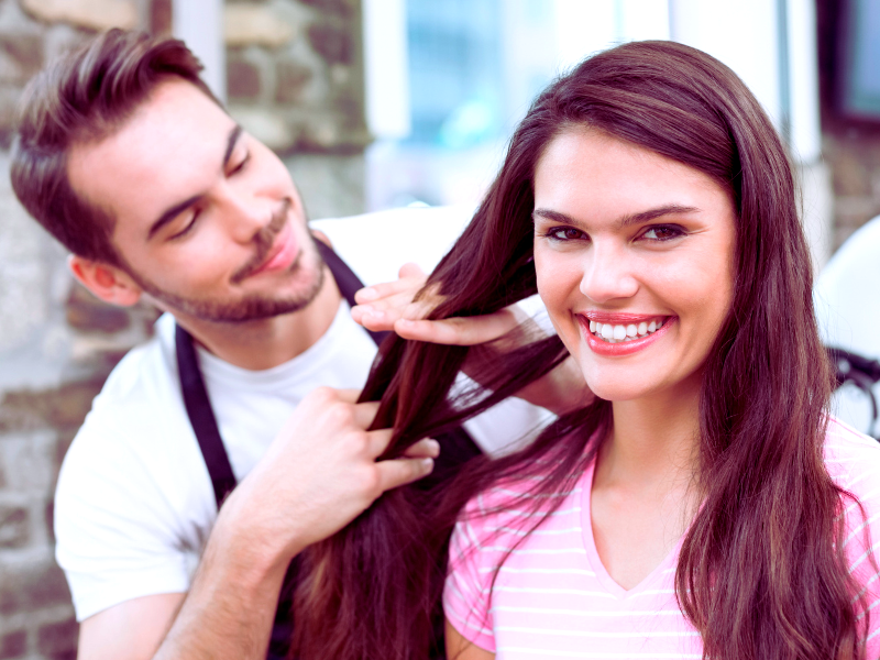 Happy salon client with shiny hair after vegan scalp detox, stylist admiring healthy results.