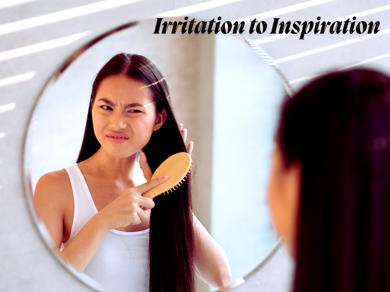 Woman brushing hair with irritated expression in mirror, showing need for gentle vegan scalp care.