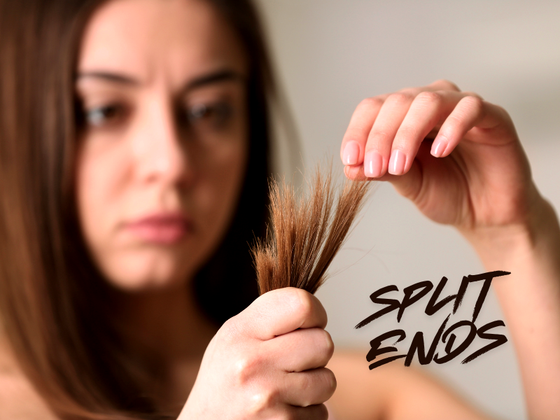 Concerned woman examining split ends, highlighting hair damage and the need for repair solutions.