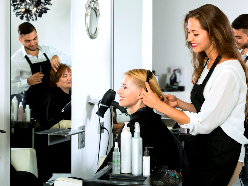Hair stylists working with smiling clients in salon—offering personalized care for all hair types.