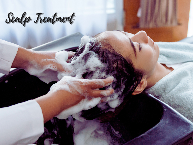 Woman receiving a relaxing, foamy scalp treatment at a salon, showcasing a deep cleanse and soothing care.