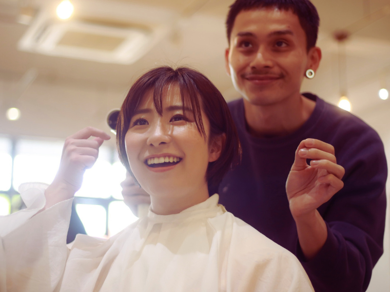 Smiling client and hairstylist sharing a joyful moment during a salon visit focused on clean beauty and care.